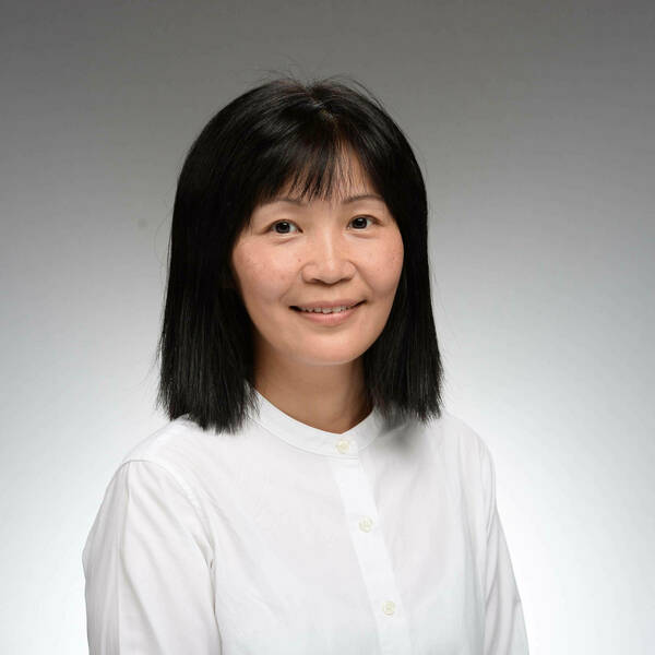 Headshot of Ming Hu, a woman with chin-length, dark hair and a white collared shirt who smiles against a gray background.